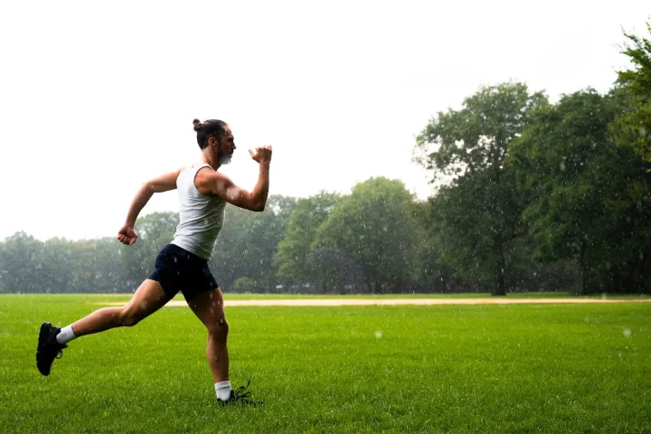 A man exercising on the grass on a rainy day